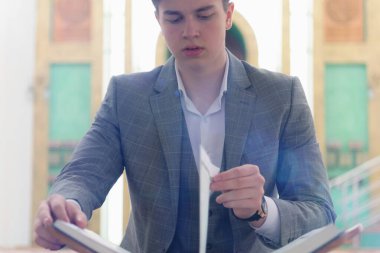 Dindar Müslüman adam camide namaz kılıyor ve kutsal kitap okuyor. 