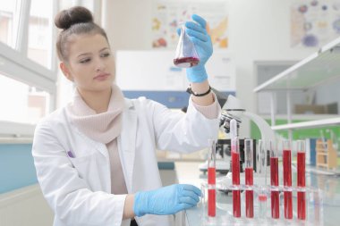 Laboratuvarda test tüpleriyle çalışan genç kadın laboratuvar bilim adamı.