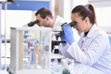 Laboratuvarda çalışan iki genç kadın ve erkek bilim adamı.