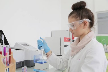 Laboratuvarda test tüpleriyle çalışan genç kadın laboratuvar bilim adamı.