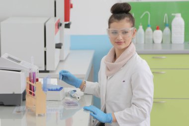 Laboratuvarda test tüpleriyle çalışan genç kadın laboratuvar bilim adamı.