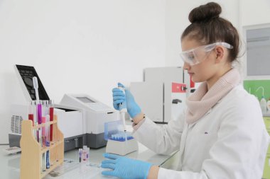 Laboratuvarda test tüpleriyle çalışan genç kadın laboratuvar bilim adamı.