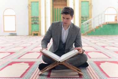 Dindar Müslüman adam camide namaz kılıyor ve kutsal kitap okuyor. 
