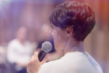 Elinde mikrofonla konuşan güzel bir iş kadını.