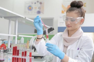 Laboratuvarda test tüpleriyle çalışan genç kadın laboratuvar bilim adamı.