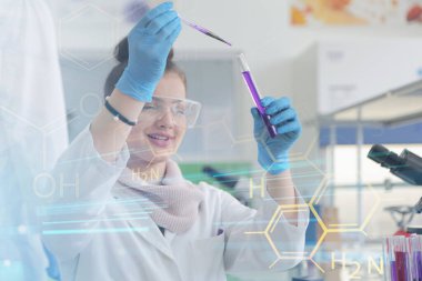 Laboratuvarda test tüpleriyle çalışan genç kadın laboratuvar bilim adamı.