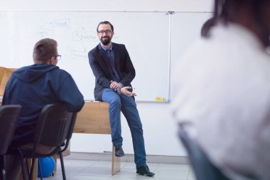 Modern okul sınıfında bir grup öğrenci profesörle birlikte okuyor.
