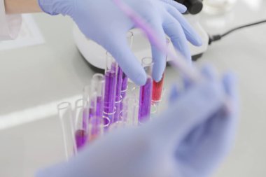 Laboratuvarda test tüpleriyle çalışan genç kadın laboratuvar bilim adamı.