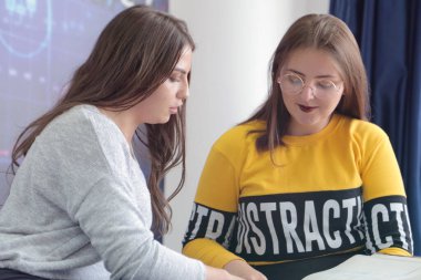 Campus life, students friendship.Two female students helping eac