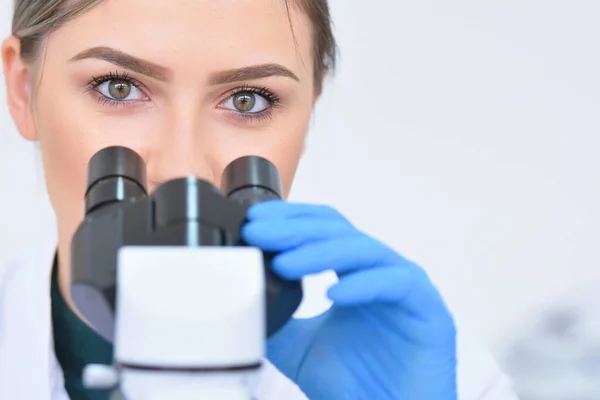 Young female male scientist looking through a microscope in a la — Stock Photo, Image
