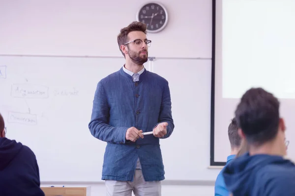 Diákok csoportja tanít a professzornál a modern osztályteremben. Férfi professzor elmagyarázza a diákoknak, és kölcsönhatásba lépnek velük, segítve a diákokat az óra alatt. — Stock Fotó