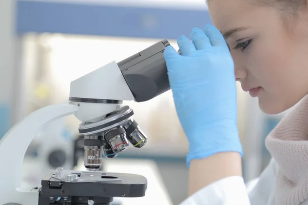 Jonge vrouwelijke mannelijke wetenschapper kijkend door een microscoop in a la — Stockfoto