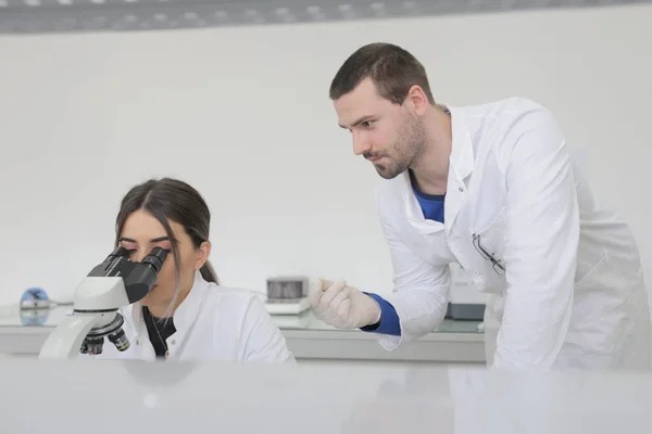 两名年轻的实验室科学家带着试管在实验室工作。 — 图库照片