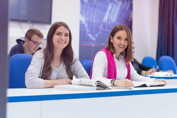 Twee vrouwelijke universiteitsstudenten in de klas zitten aan hun bureau — Stockfoto