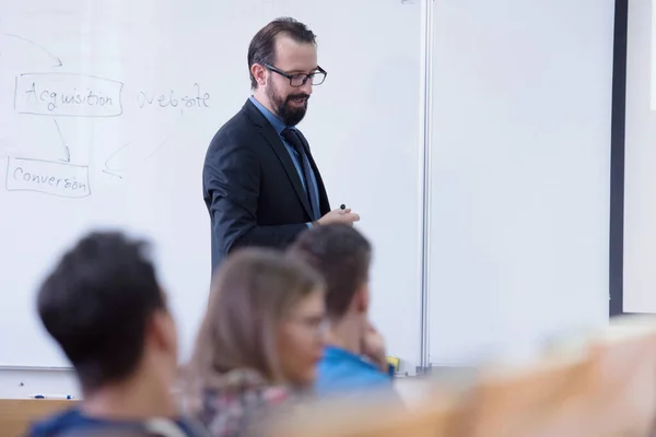 Skupina studentů studuje u profesora v moderní školní třídě — Stock fotografie