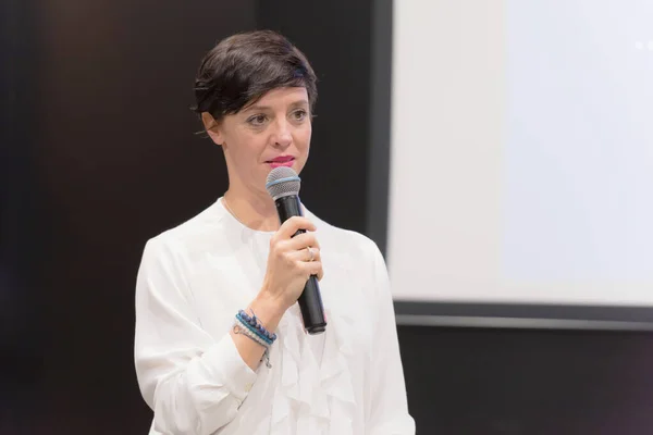 Beautiful business woman with microphone in her hand speaking at — Stock Photo, Image