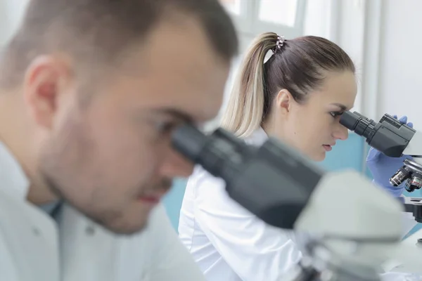 Dos jóvenes científicos de laboratorio que trabajan en el laboratorio con tubos de ensayo a — Foto de Stock