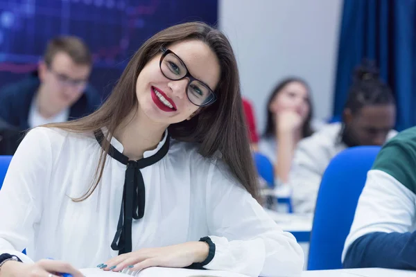 Universitaire vrouwelijke student in de klas zit aan haar bureau wenden tot s — Stockfoto