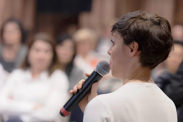 Beautiful business woman with microphone in her hand speaking at — Stock Photo, Image