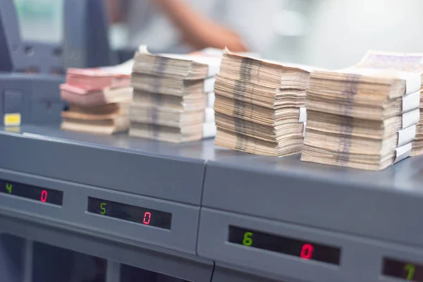 Bank employees sorting and counting money inside bank vault. Lar