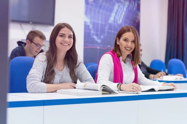 Dos alumnas universitarias en clase se sientan en su escritorio turni —  Fotos de Stock