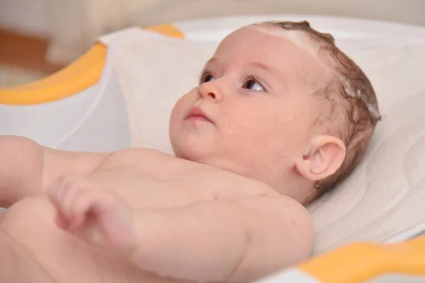 Hübsches drei Monate altes Mädchen, das von seiner Mutter zu Hause gebadet wird, europäisches Kind. — Stockfoto