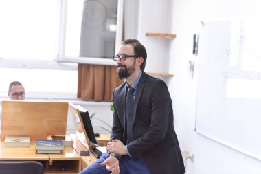 Erkek profesör öğrencilere ders veriyor ve onlarla iletişim kuruyor.