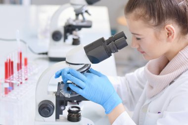 Genç bayan bilim adamı mikroskopla Los Angeles 'a bakıyor.