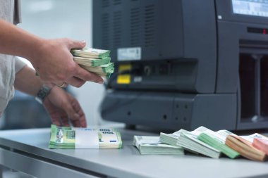 Banka çalışanları banka kasasında para sıralayıp sayıyor.