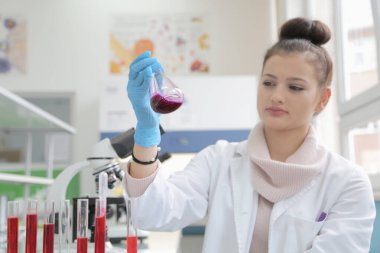 Laboratuvarda test tüpleriyle çalışan genç kadın laboratuvar bilim adamı.