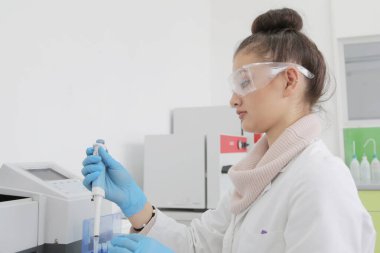 Laboratuvarda test tüpleriyle çalışan genç kadın laboratuvar bilim adamı.