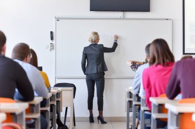 Bayan profesör öğrencilere dersi açıkla ve onunla iletişim kur.