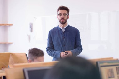 Modern okul sınıfında bir grup öğrenci profesörle birlikte okuyor.