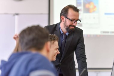 Erkek profesör öğrencilere ders veriyor ve onlarla iletişim kuruyor.