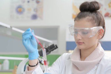 Laboratuvarda test tüpleriyle çalışan genç kadın laboratuvar bilim adamı.