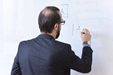 Erkek profesör öğrencilere ders veriyor ve onlarla iletişim kuruyor.