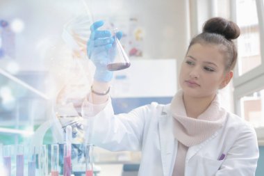 Laboratuvarda test tüpleriyle çalışan genç kadın laboratuvar bilim adamı.