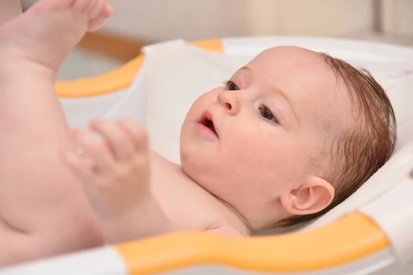 Hübsches drei Monate altes Mädchen, das von seiner Mutter zu Hause gebadet wird, europäisches Kind. — Stockfoto