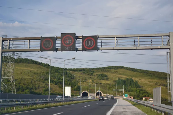 Autobahn- und Straßenschilder mit Blick auf den modernen Tunnel bei bewölktem Himmel — Stockfoto