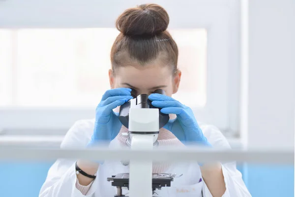 Joven científica masculina mirando a través de un microscopio en a la — Foto de Stock