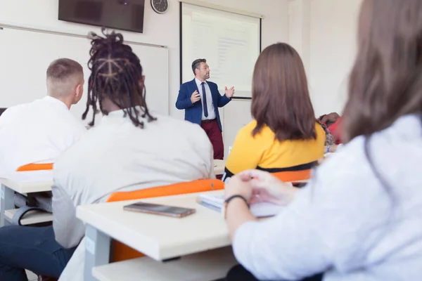 Mužský profesor vysvětlit lekci studentům a komunikovat s nimi — Stock fotografie