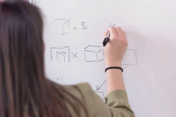 Young college female student writting on the chalkboard during a
