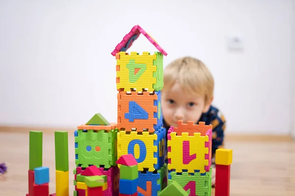 Bambino prescolare che gioca con blocchi di giocattoli colorati. Ragazzo che gioca — Foto Stock