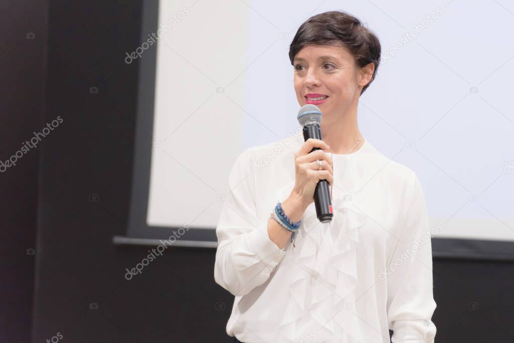 Beautiful business woman with microphone in her hand speaking at