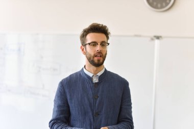 Erkek profesör öğrencilere ders veriyor ve onlarla iletişim kuruyor.