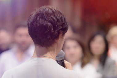 Elinde mikrofonla konuşan güzel bir iş kadını.