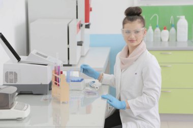 Laboratuvarda test tüpleriyle çalışan genç kadın laboratuvar bilim adamı.