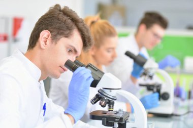 Laboratuvarda deney tüpleriyle çalışan bir grup bilim adamı.