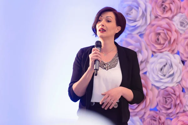 Beautiful business woman with microphone in her hand speaking at