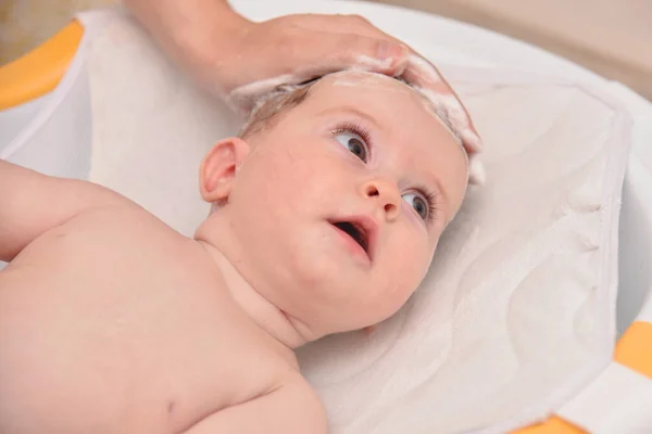 Hübsches drei Monate altes Mädchen, das von seiner Mutter zu Hause gebadet wird, europäisches Kind. — Stockfoto